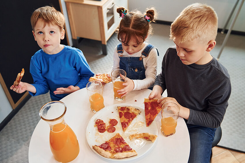 three-children-sitting-indoors-by-the-table-and-ea-6NE33KH